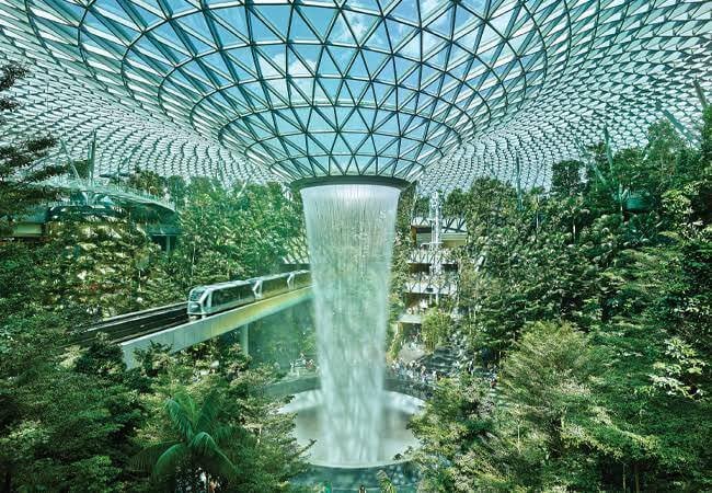 The massive indoor waterfall surrounded by trees inside Jewel Changi Airport